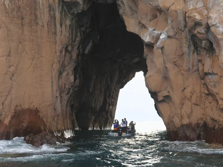 Panga passing through a rock arch, San Cristóbal