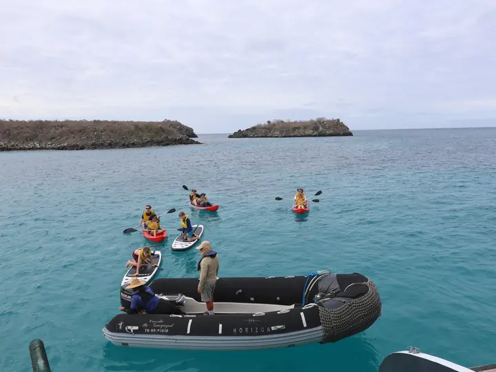 Kayaks and a panga on calm turquoise water during a Galápagos cruise