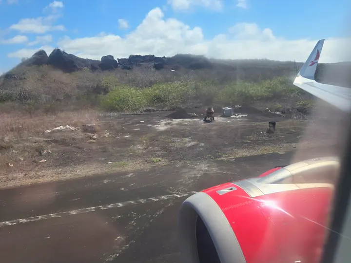 Wing of the plane over the dry coast on approach to San Cristóbal